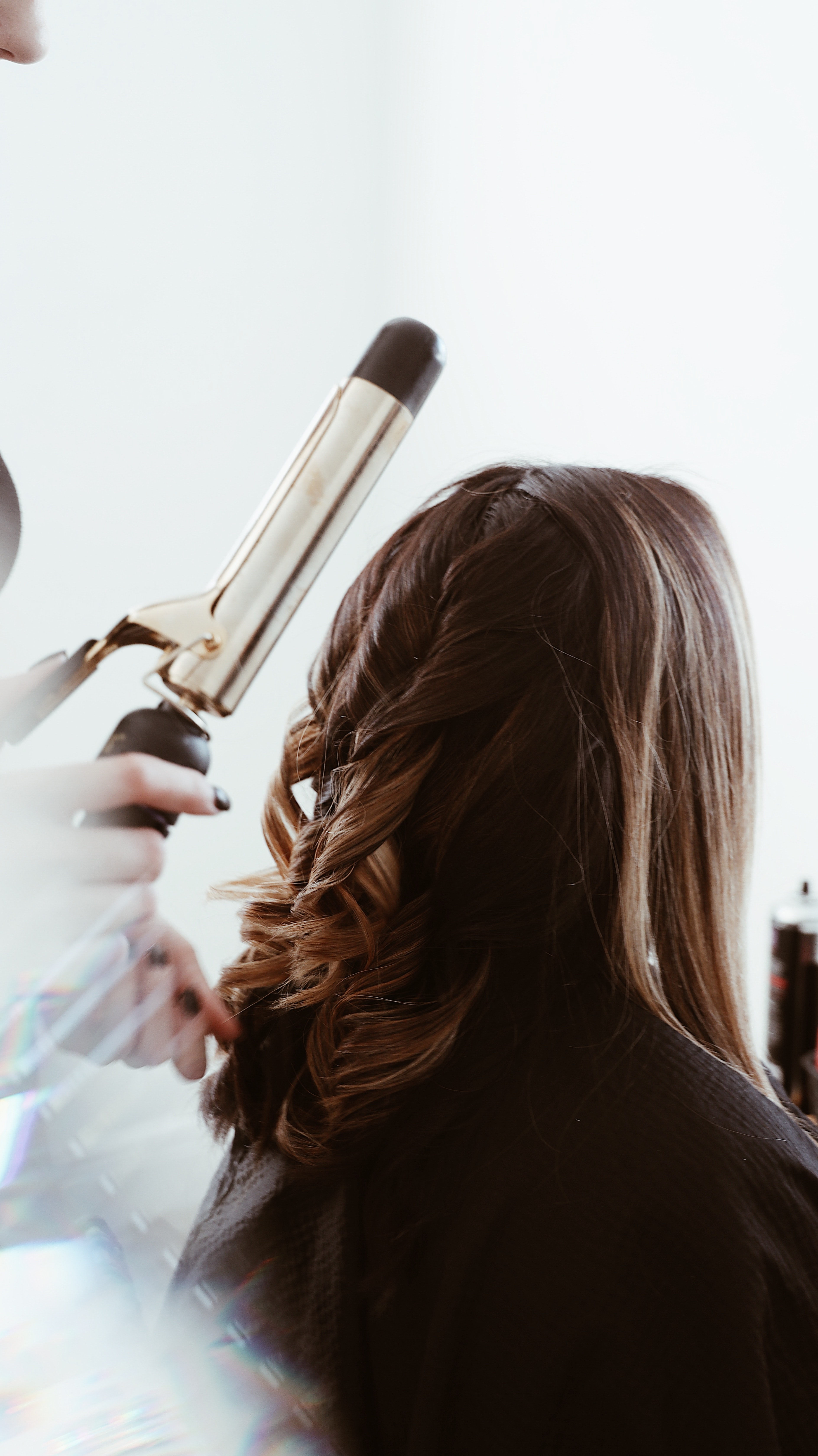 Back of woman's head as hairdresser curls her hair